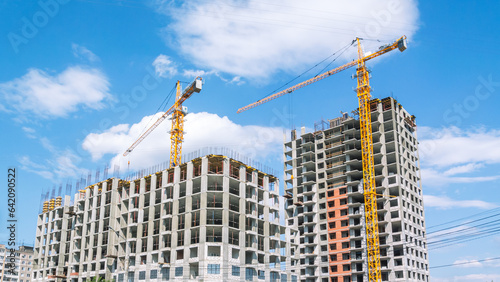 Tableau sur toile A tower construction crane on the background of a blue sky with clouds
