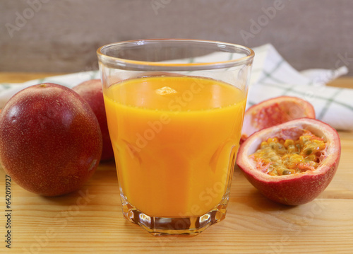 Glass of Mouthwatering Fresh Passion Fruit Juice with Heap of Whole Fruits in the Backdrop