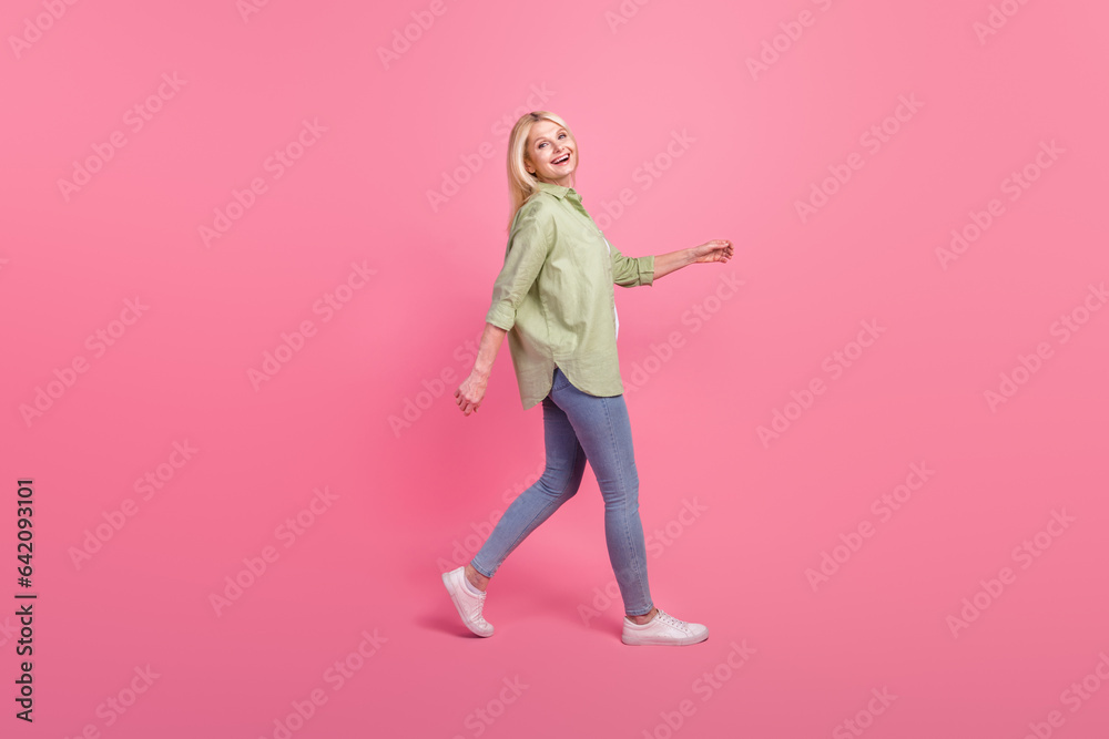 Profile side full length photo of cheerful glad lady dressed stylish clothes laughing going empty space isolated on pink color background