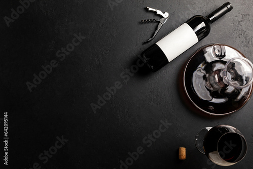 Decanter, glass and bottle with red wine on black. Flat lay