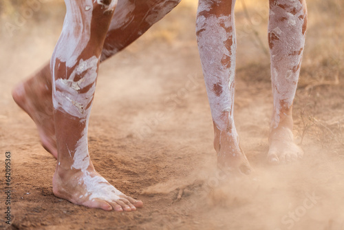 Feet of First nations people dancing in oka paint to tell the story kicking up dust photo