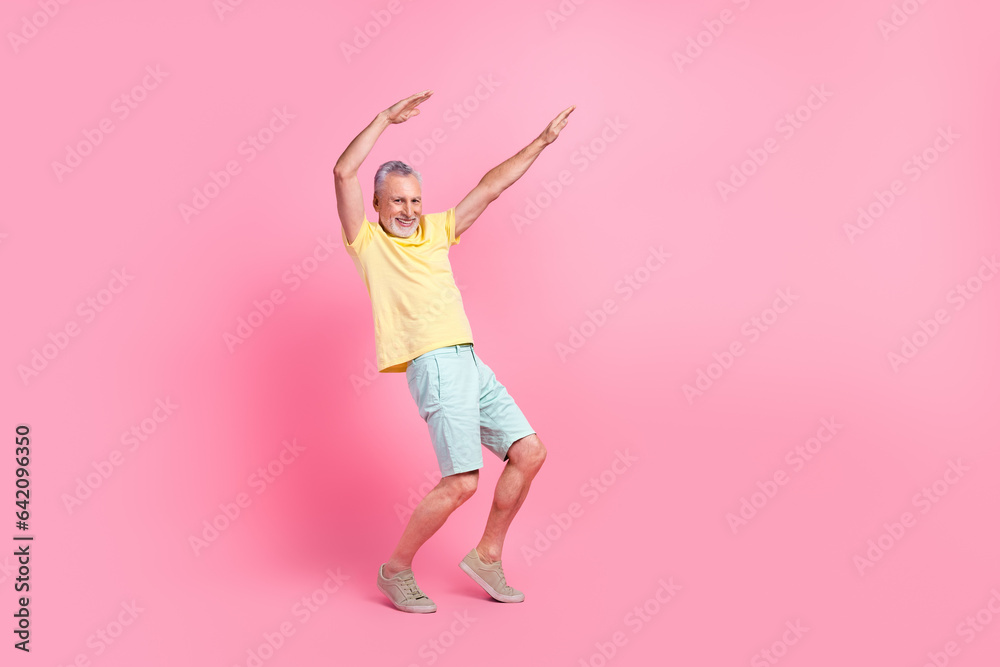 Full body photo of model senior funky man raise hands up dancing tiptoes good vibe atmosphere discotheque isolated on pink color background Full body photo of model senior funky man raise hands up dancing tiptoes good vibe atmosphere discotheque isolated on pink color background