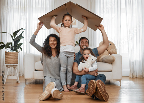 Parents, children and cardboard roof in portrait, smile or excited for security, real estate or fresh start in family home. Mother, dad and kids on floor, box and happy together for support in house