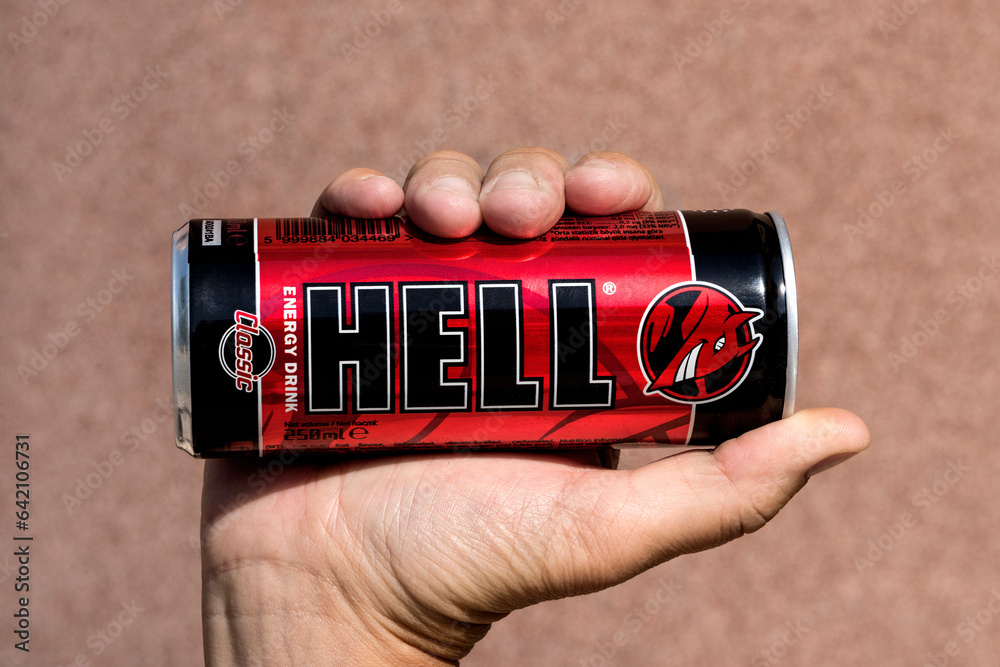 Red black tin can of famous HELL energy drink in a right hand