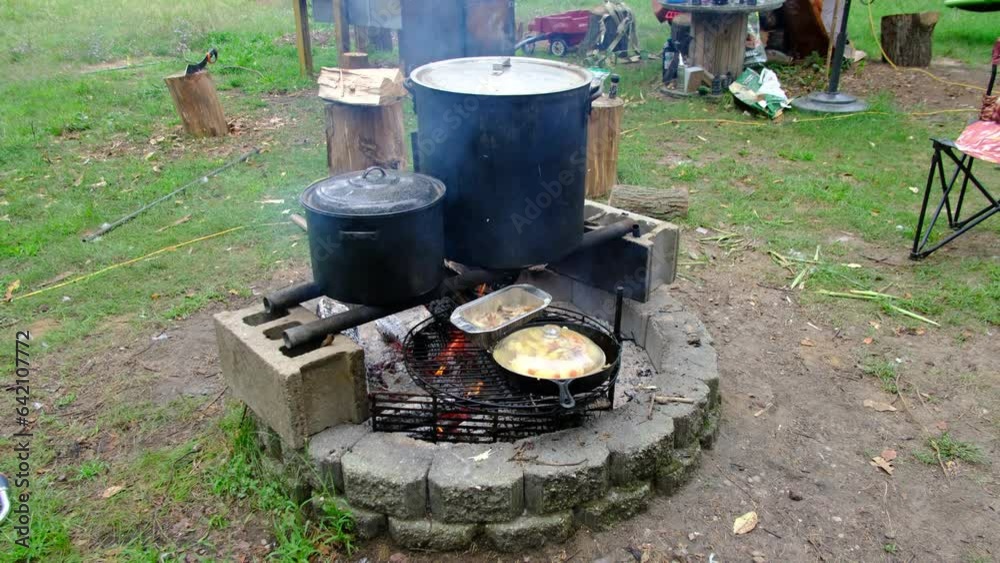 Variety of food being cook for animals and for human consumption on fire pit in pots and cast iron skillet and aluminum tray. Variety of food being cook for animals and for human consumption on fire pit in pots and cast iron skillet and aluminum tray.