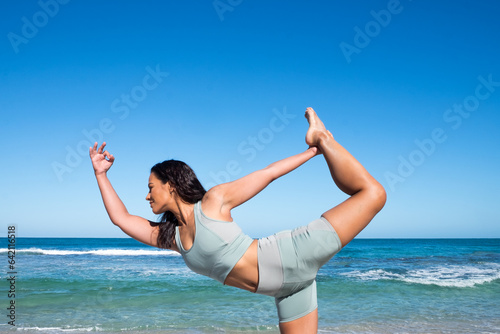 Athletic woman in standing yoga pose with ocean in background photo