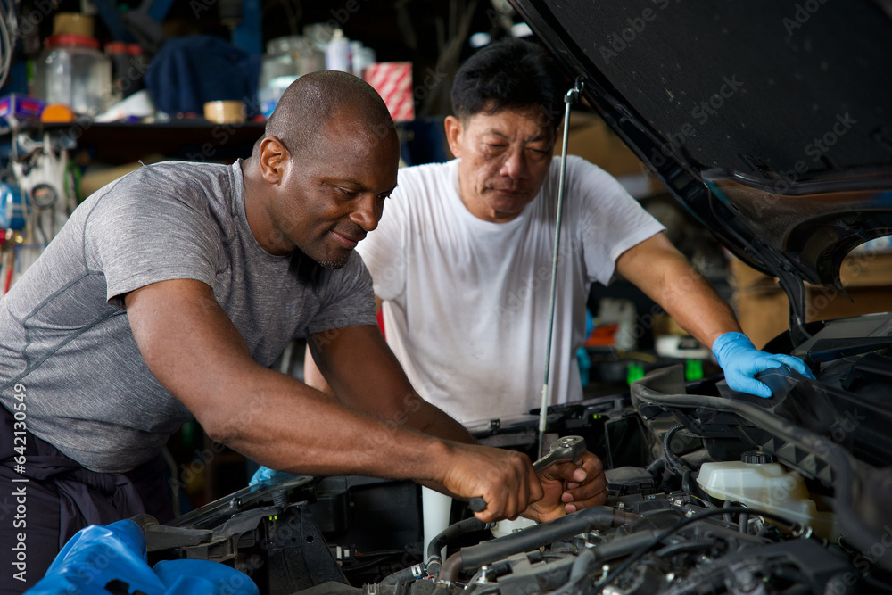 African mechanics or workers checking and fixing a car in garage African mechanics or workers checking and fixing a car in garage