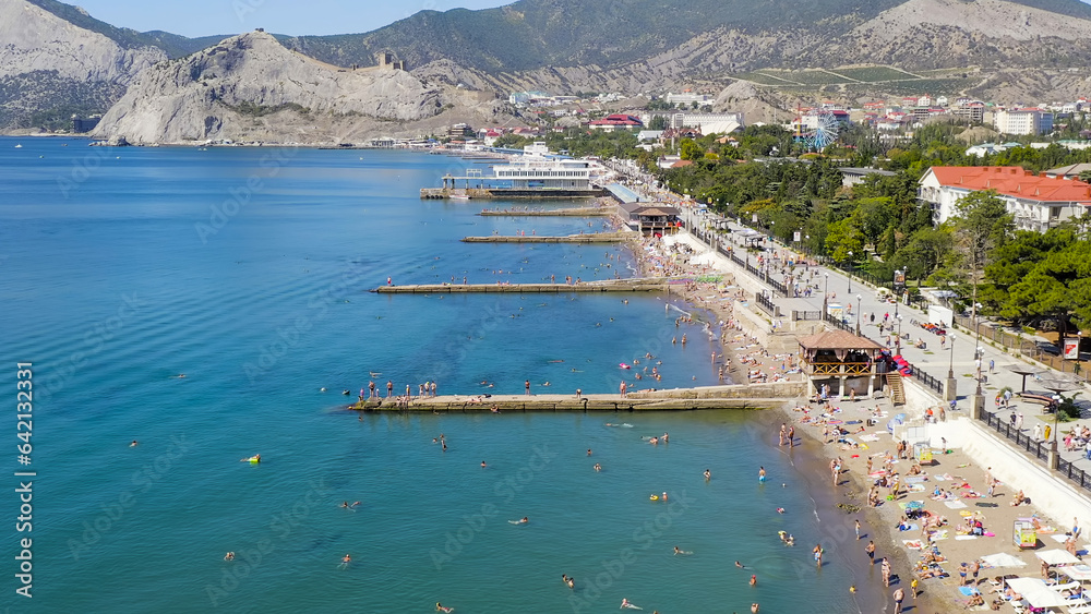 Sudak, Crimea - September 15, 2020: Embankment of Sudak. Black sea coast with beaches and people, Aerial View