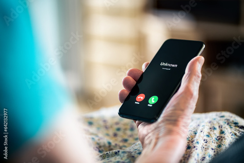 Old woman and phone call with hidden mobile number. Senior mature lady and fraud and scam caller. Love and romance hoax. Holding smartphone in hand. Catfish or scammer. Phishing concept.
