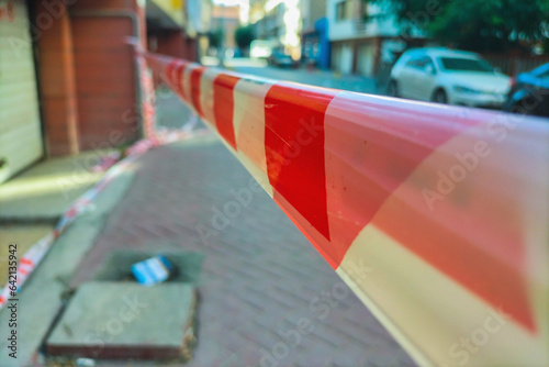 Red and white restrictive tape on the street, stretched to restrict access to this area of the street, yard. Element in criminal investigations, chronicle, news, construction work