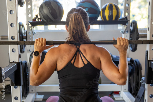 Strong, muscular woman lifting weights in gym during workout. Competitive female weightlifter