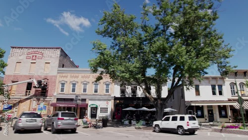 Car passenger point of view pov  and moving shot looking out at small businesses, older buildings, and street parking in small American town of Granville, Ohio
