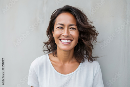 Smiling Filipino woman posing against a grey wall.