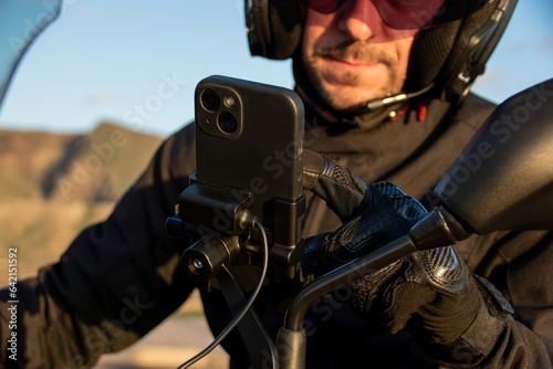 Biker setting the route on the gps map of his smartphone anchored to the handlebar.