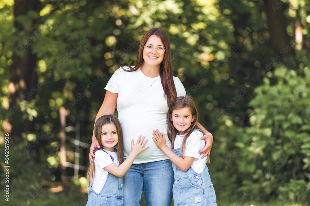 Pregnant woman posing in the parkwith her two childs Pregnant woman posing in the parkwith her two childs