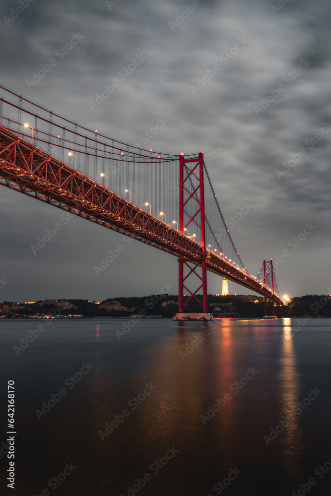 Vertical image of the 25 April bridge (Ponte 25 de Abril) located in Lisbon, Portugal, crossing the Targus river at night.