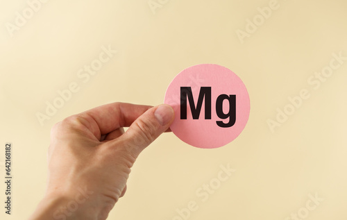 Mg text on yellow round card in hand on yellow background