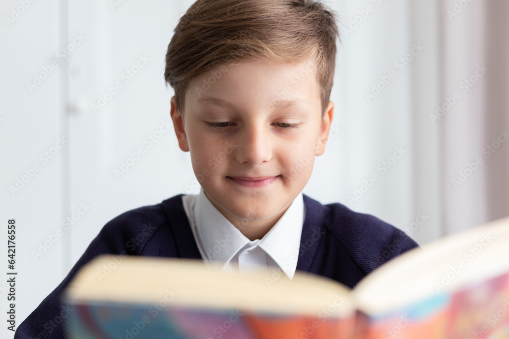 Happy schoolboy sitting at desk reading the book. Back to school concept. High quality photo Happy schoolboy sitting at desk reading the book. Back to school concept. High quality photo