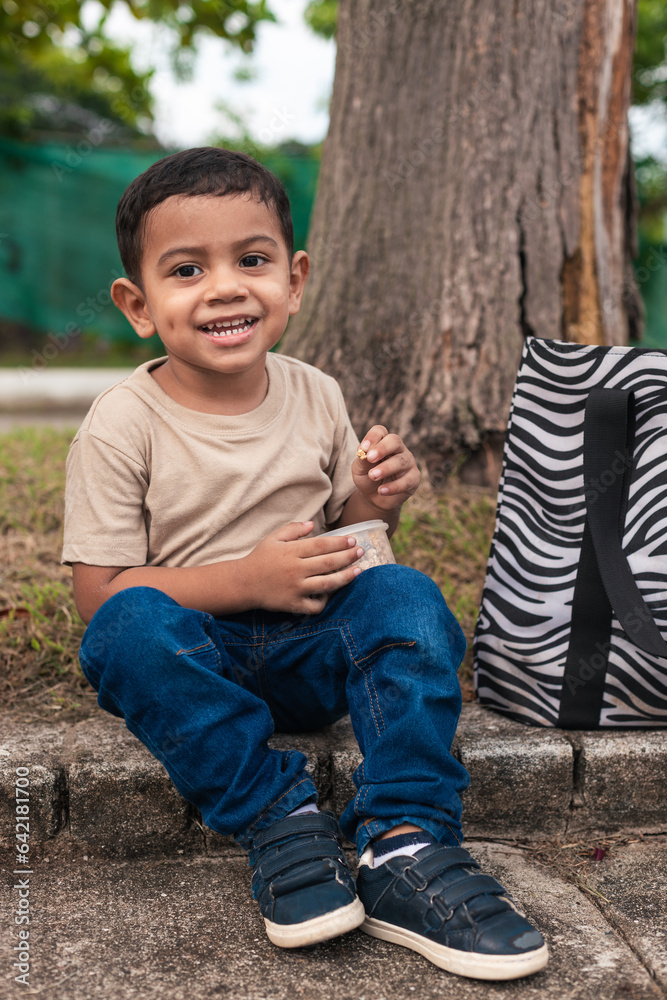 latin boy sitting on the floor, gesture of happiness, wearing khaki sweater latin boy sitting on the floor, gesture of happiness, wearing khaki sweater
