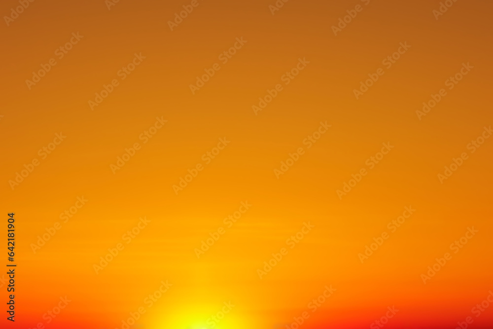 Naklejka premium The sun rising over the horizon against an orange-red sky.