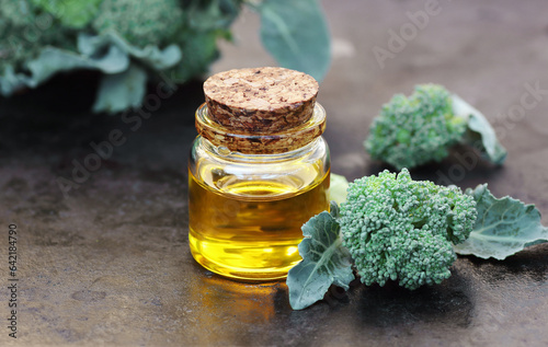 Broccoli seed oil with fresh vegetable on black background, closeup, natural cosmetics ingredient for homemade cosmetic beauty products, skincare, spa, natural hair care concepts photo