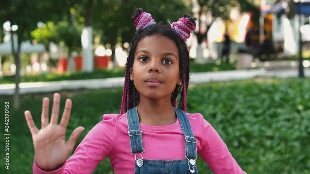 An African-American girl with pink braids acts like a doll on a city street.Slow motion. An African-American girl with pink braids acts like a doll on a city street.Slow motion.