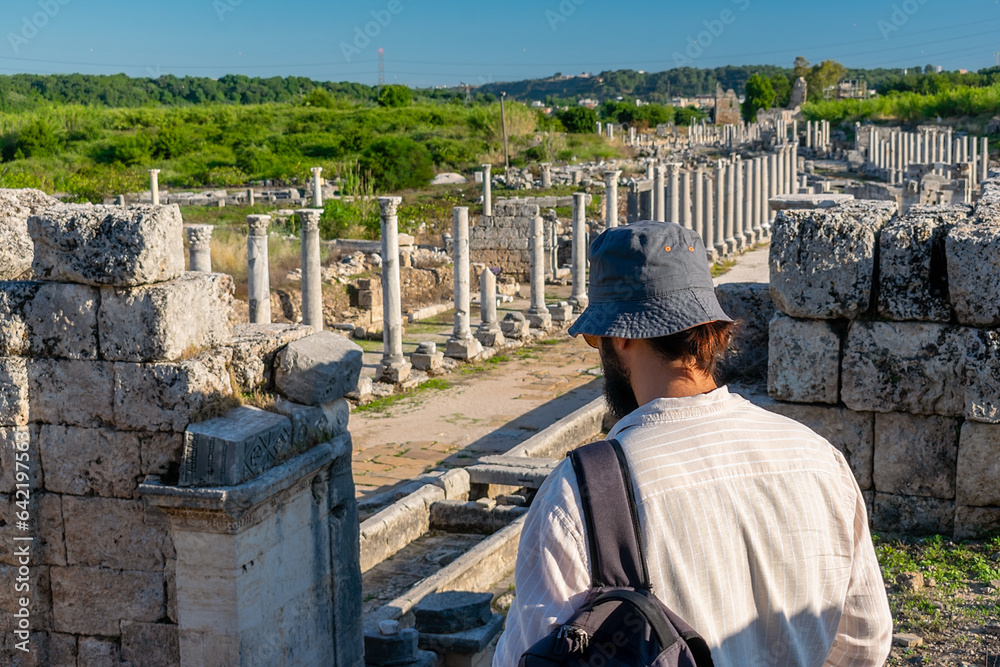 A male tourist walks around the ancient ancient city of Perge. A man of Mediterranean appearance admires the ancient city of Perge.