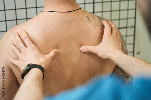 Physical therapist performing thoracic spine palpation in adult person