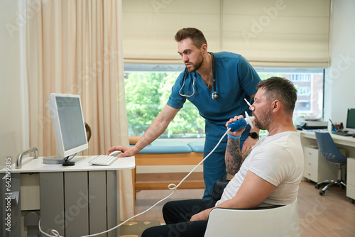 Adult man taking spirometry test in presence of doctor photo