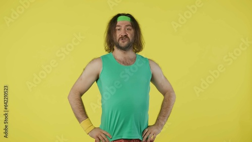 Man in green top and headband posing, looking at the camera. Isolated on yellow background. © kinomaster