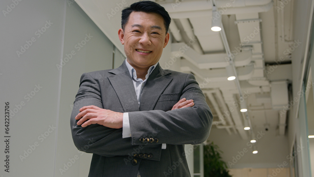 Executive businessman Asian middle-aged man stand in modern company office. Korean chinese japanese male crossing hands looking at camera confident ceo director business owner smiling cheerful smile Executive businessman Asian middle-aged man stand in modern company office. Korean chinese japanese male crossing hands looking at camera confident ceo director business owner smiling cheerful smile