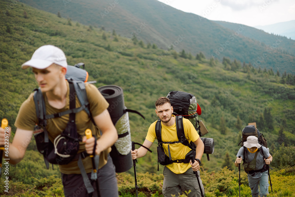 group of 3 hikers climbing the foot of the mountain to its peak, selective focus
