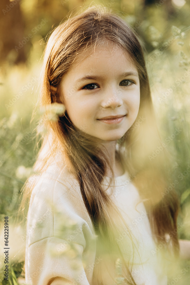 Naklejka premium young happy and smiling little girl spending a weekend on a walk in summer park. selective focus, noise effect