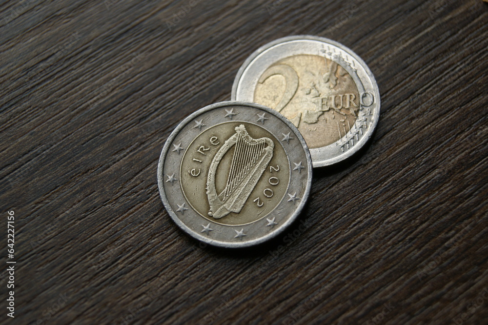 Irish 2 euro coins. Used coins on a dark wooden table Irish 2 euro coins. Used coins on a dark wooden table