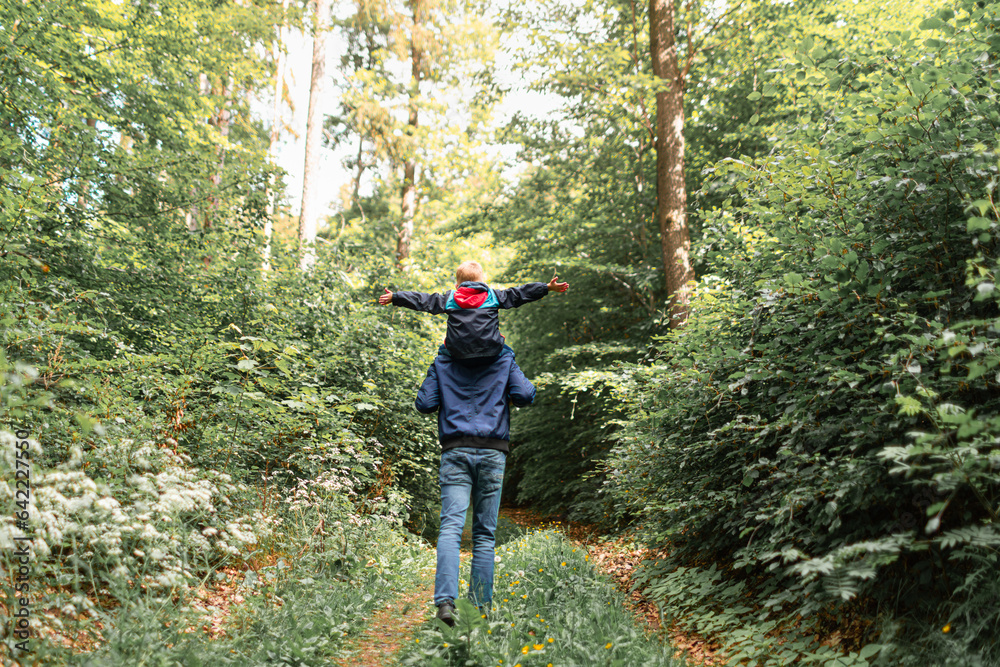 Happy father and son walking in the woods enjoying natures beauty Happy father and son walking in the woods enjoying natures beauty