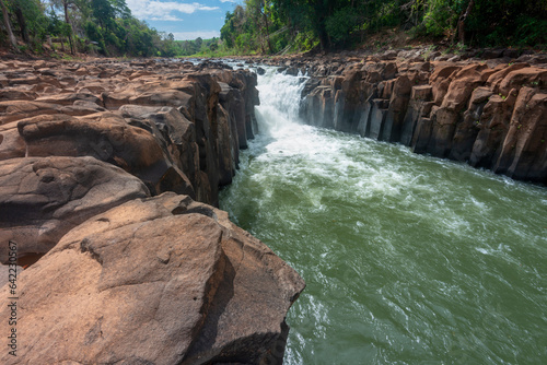 Waterfall cascades over jagged rocks and boulders at Maak Ngaew falls near Pakse Southern Laos.