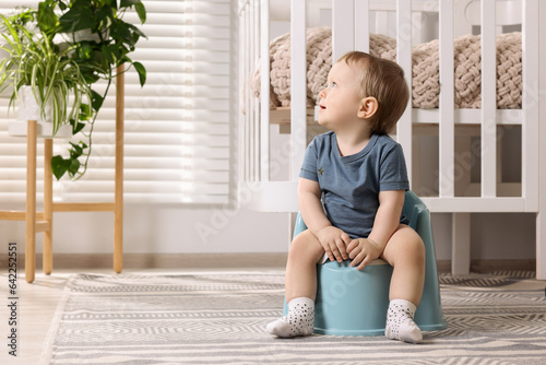 Quadro su tela Little child sitting on plastic baby potty indoors
