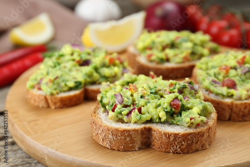 Slices of bread with tasty guacamole on wooden table, closeup