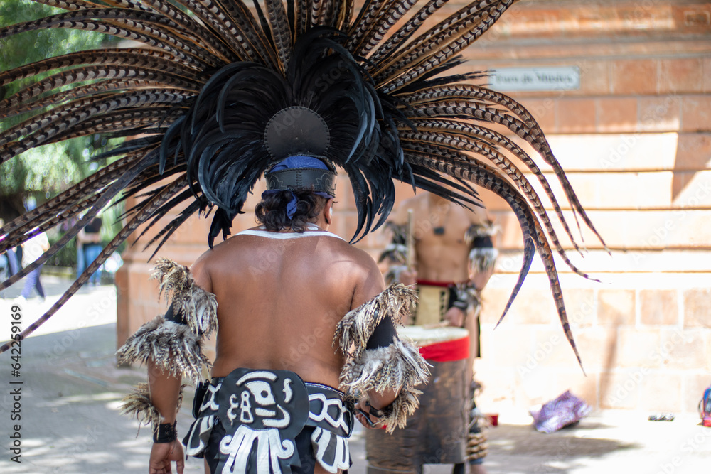 street mexican performer using a big feathered headdress while dancing in public