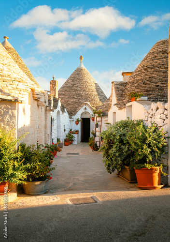 Characteristic Alberobello trullo by day, blue sky with clouds, vertical