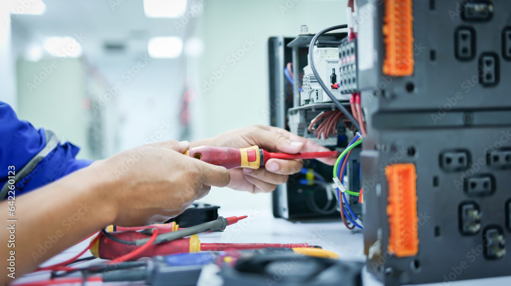 Electrical engineer checking and fixing automatic control switchboard to resume normal operation, industrial technology work concept and work safety.