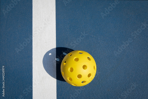 Yellow Pickleball on a Pickleball court.