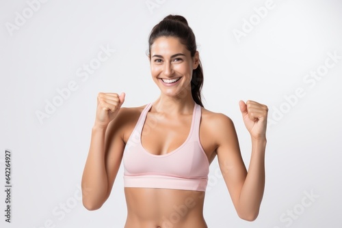 Portrait of a smiling sportswoman in pink sportswear showing her thumb up and her biceps isolated on a white background and Looking at the camera.