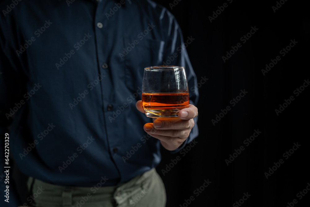 Close up shot of asian businessman holding glass of whiskey, alcohol, wine in hand with depression and sadness in face of financial or family problems. Close up shot of asian businessman holding glass of whiskey, alcohol, wine in hand with depression and sadness in face of financial or family problems.