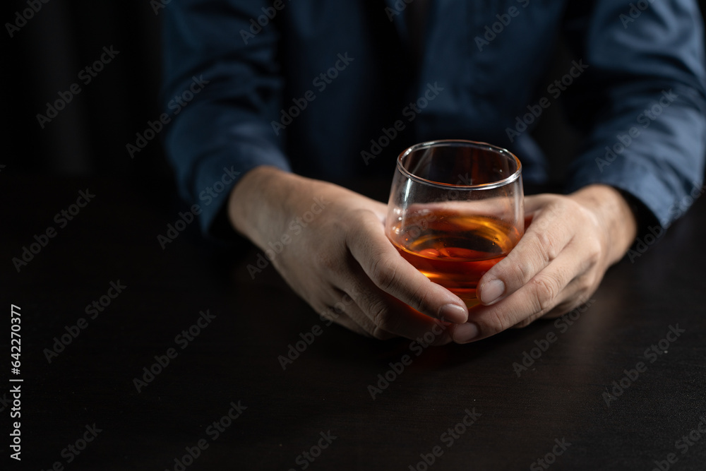 Asian businessman stressed at work failed business problem paperwork Desperate man holding a glass of alcohol Sitting at the desk late at night in the office Depressed and hopeless concept.