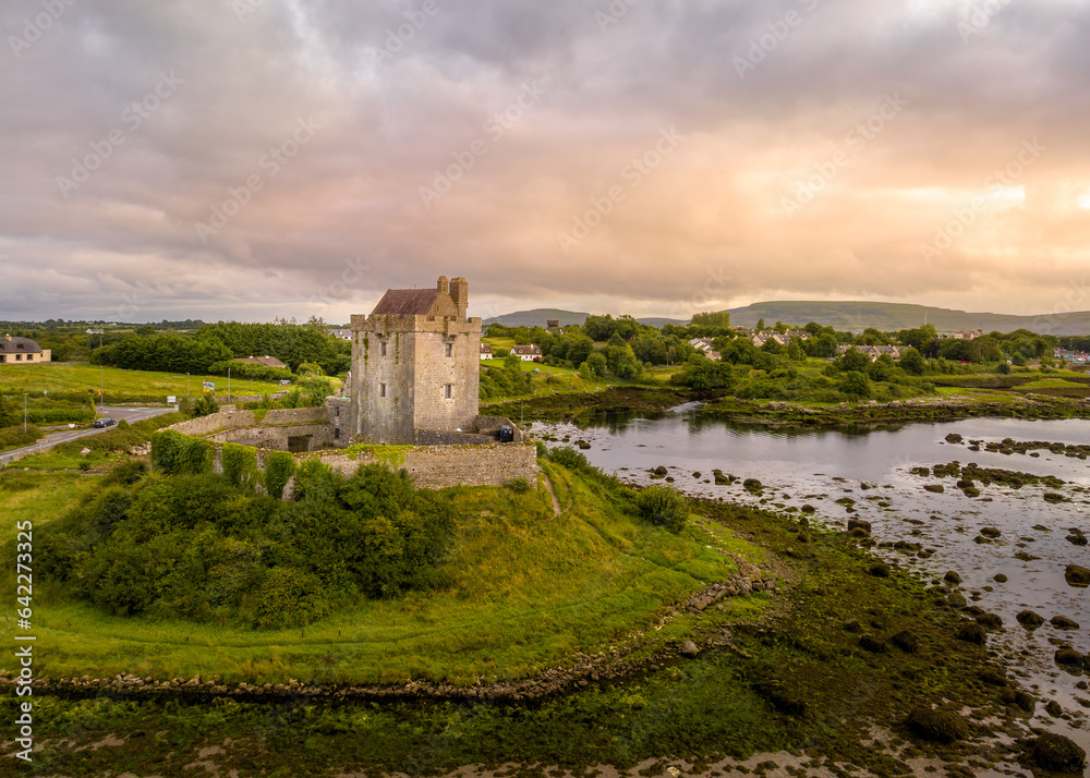 Aerial view of Dunguaire Castle is a 16th-century tower house on the southeastern shore of Galway Bay in County Galway, Ireland, near Kinvara with dramatic sunset sky