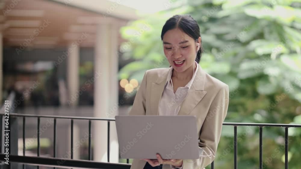 The asian business woman using laptop computer for working and operation in outside office having remote video call virtual meeting or online distance at outdoor.