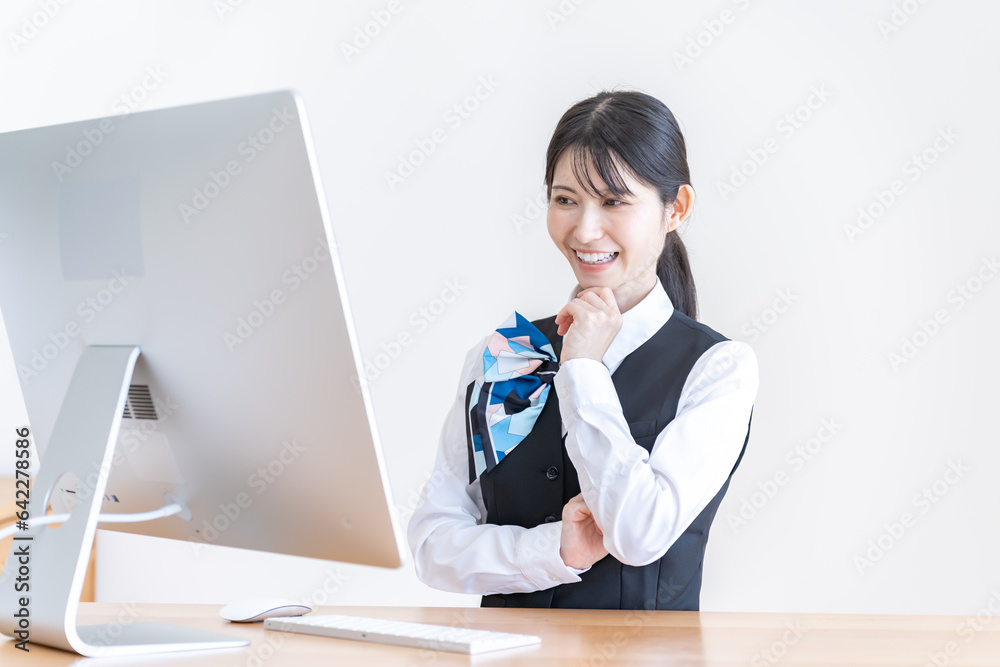 パソコンの前で考える制服を着た日本人女性