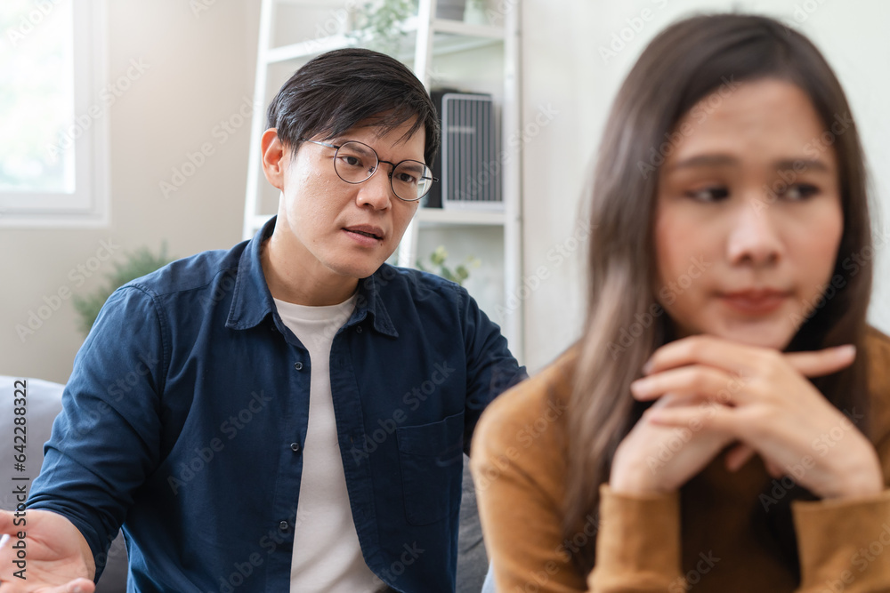 Family problem concept, Asian wife and husband sitting back to back in the living room at home have problems in a relationship and have an argument Family problem concept, Asian wife and husband sitting back to back in the living room at home have problems in a relationship and have an argument