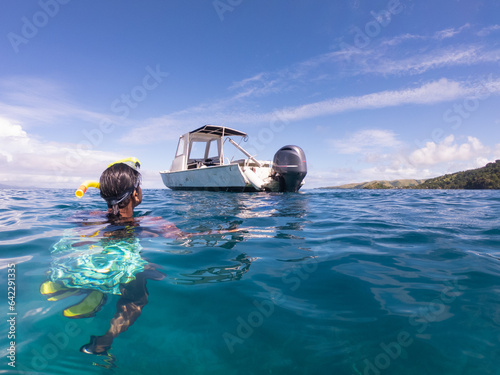 Indian woman snorkeling next to boat in the blue tropical waters of Fiji